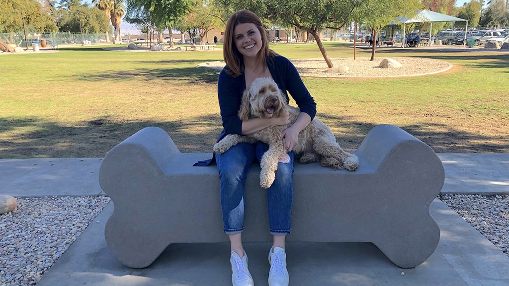 woman with dog on lap sitting on bone shaped bench